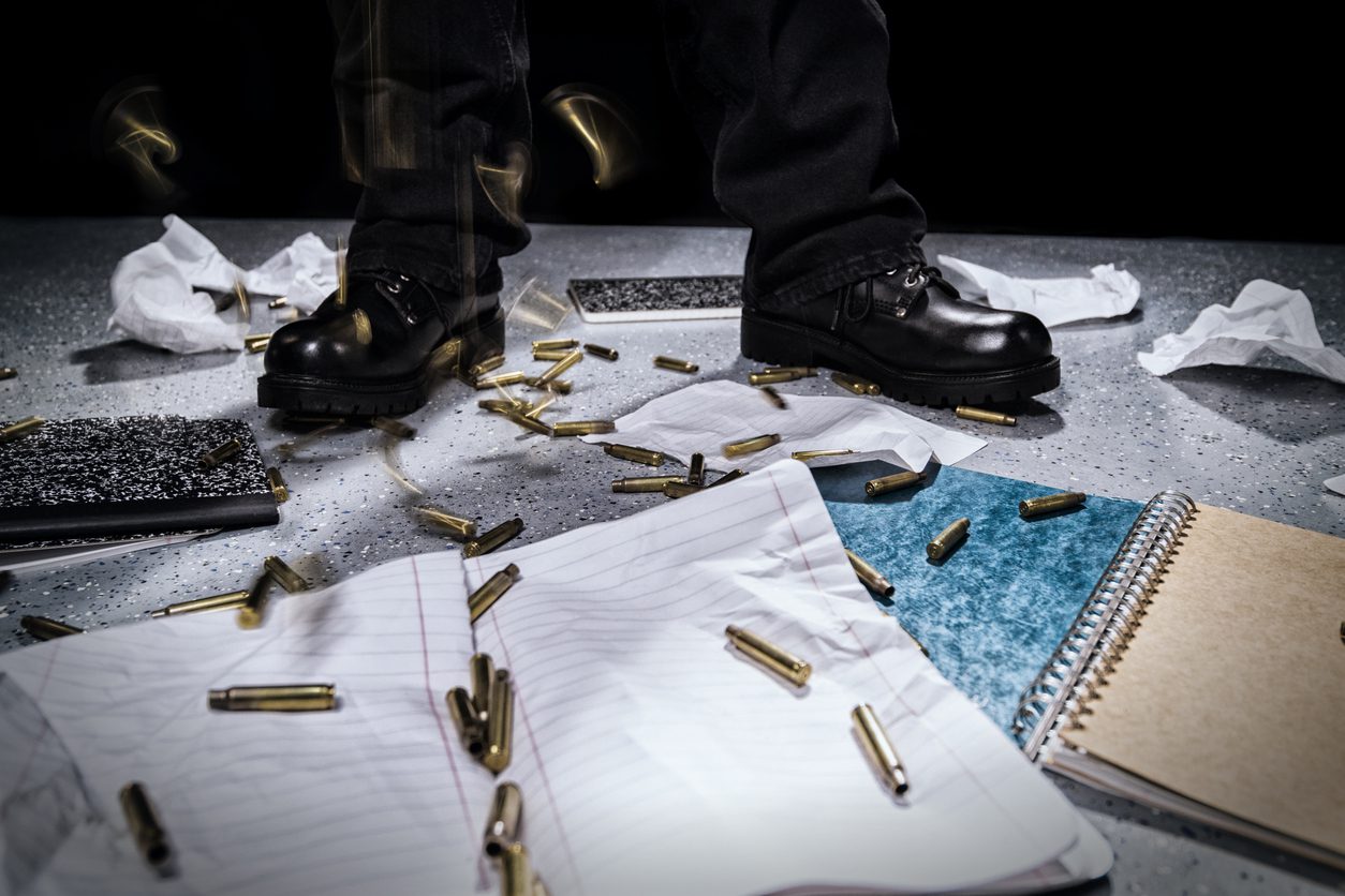 Shooter's feet as bullet casings rain down on school notebooks.
