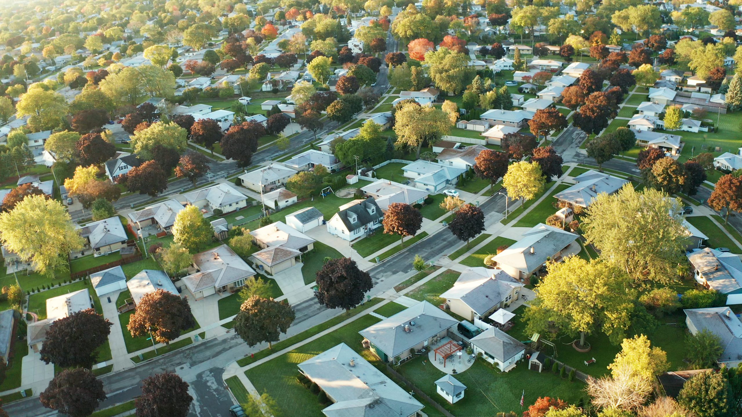Vista aérea de casas residenciales en otoño (octubre). Barrio americano, suburbio. Bienes raíces, tomas de drones, puesta de sol, mañana soleada, luz solar, desde arriba