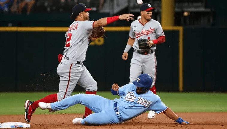 Marcus Semien #2 of the Texas Rangers is out at second base as Luis Garcia #2 of the Washington Nationals throws to first base to complete the double play during the first inning at Globe Life Field on June 26, 2022