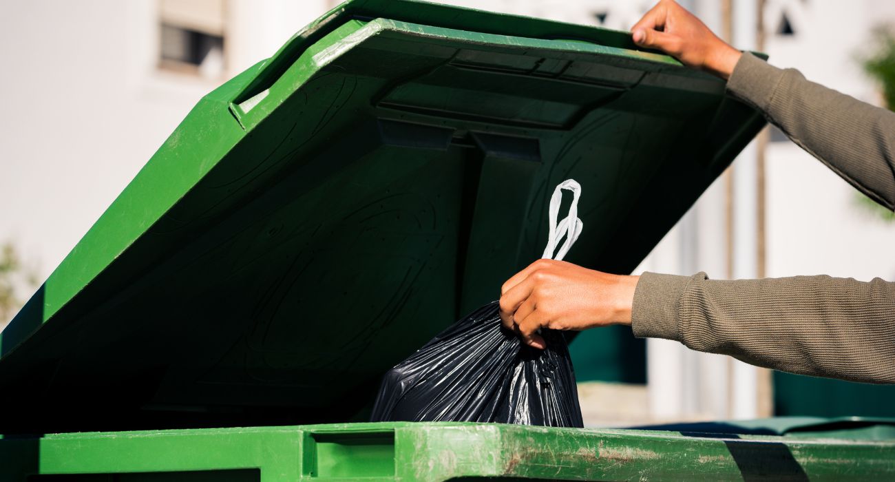 Person throwing away trash in bin