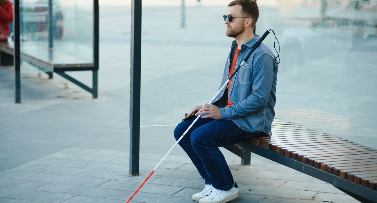 Blind man sitting at a bus stop