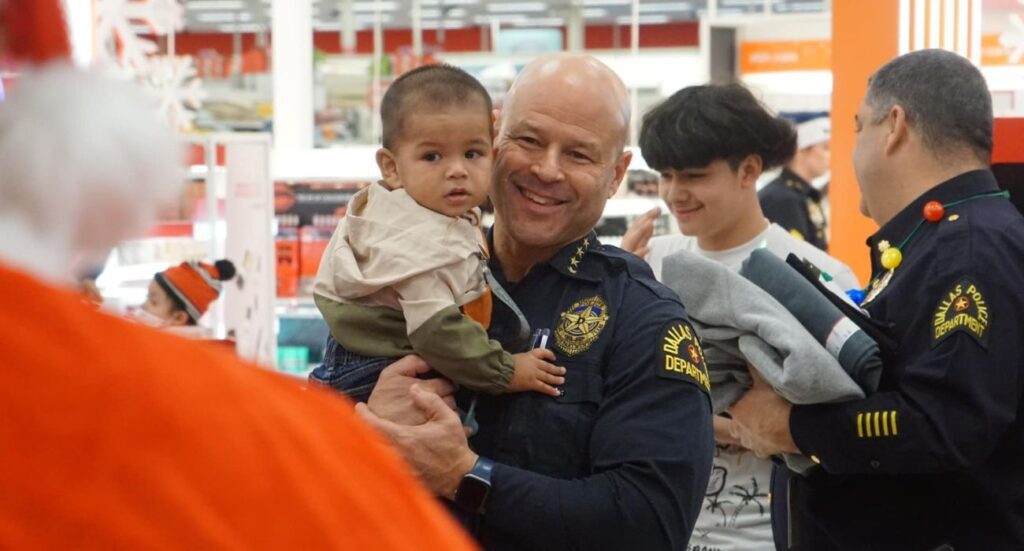 Dallas Police Chief Eddie Garcia holds a child facing Santa Claus at Target during the Heroes and Helpers shopping event.