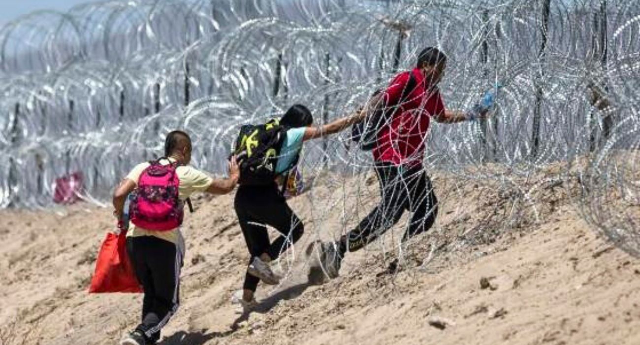 Unlawful migrants walk through razor wire in El Paso, Texas.
