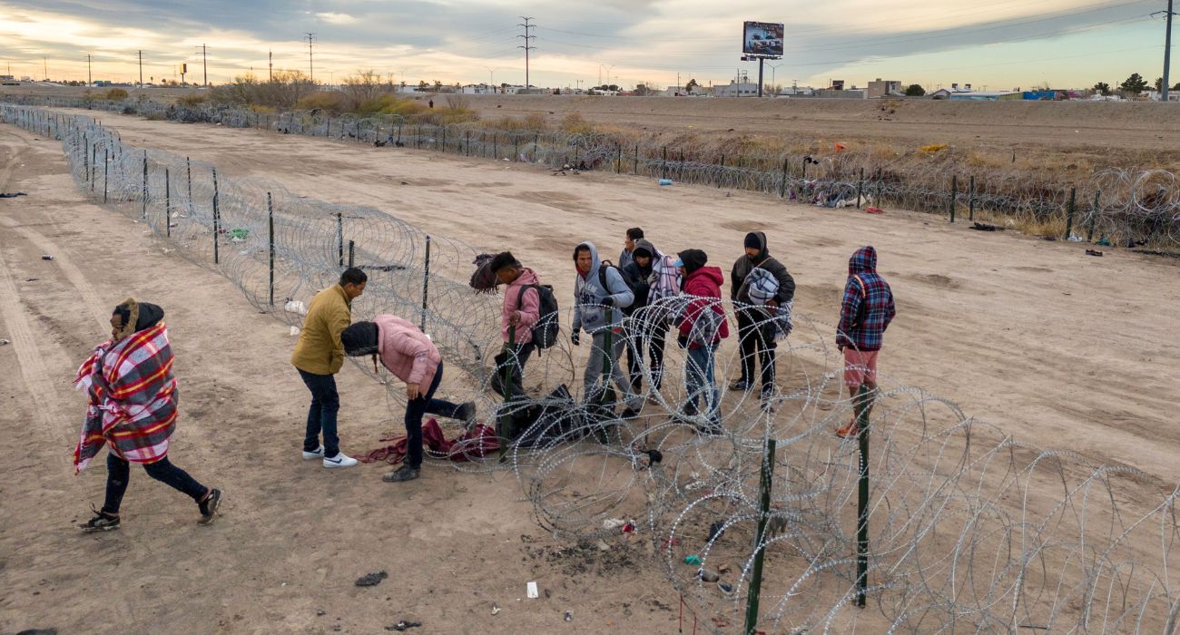 Unlawful migrants pass through razor wire after crossing the Rio Grande into El Paso, Texas