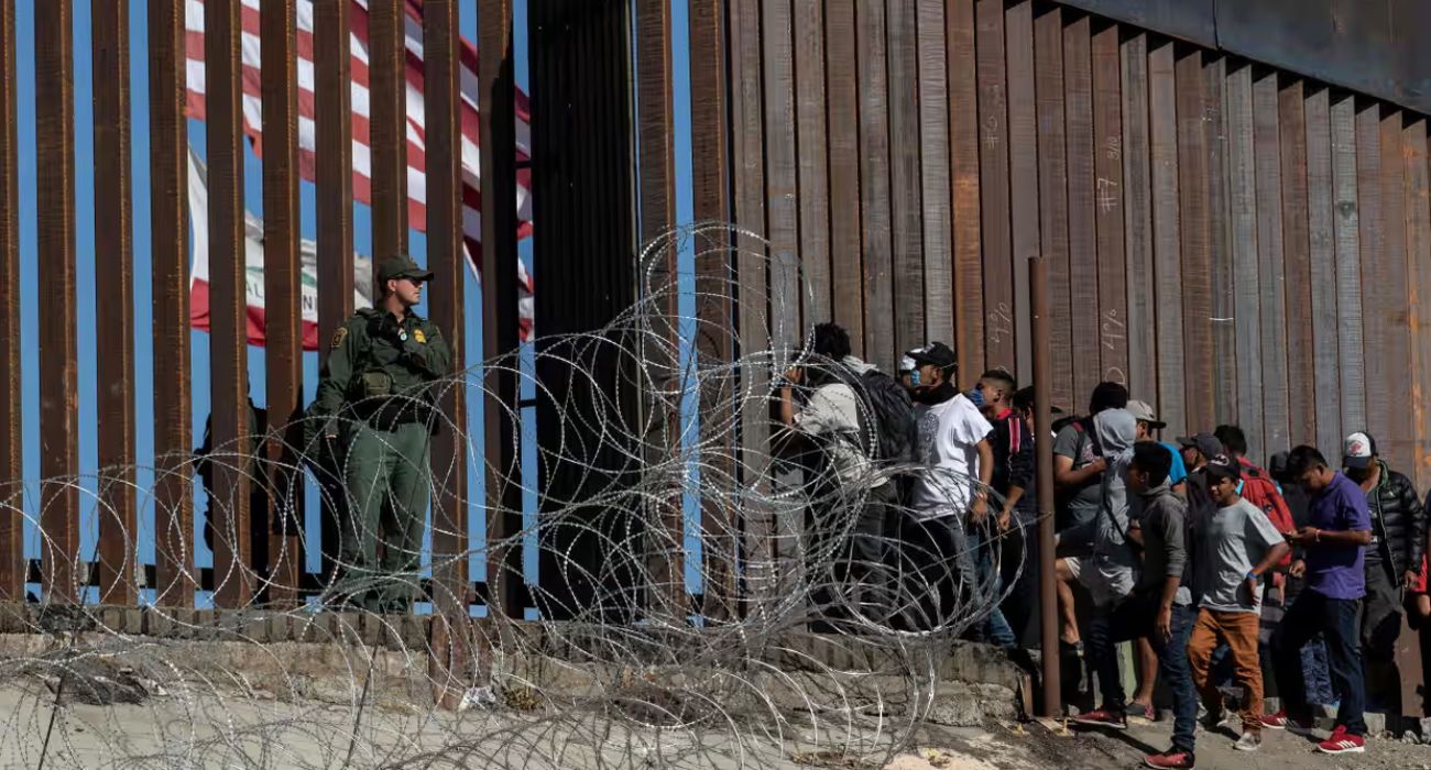 Unlawful migrants look through a border fence