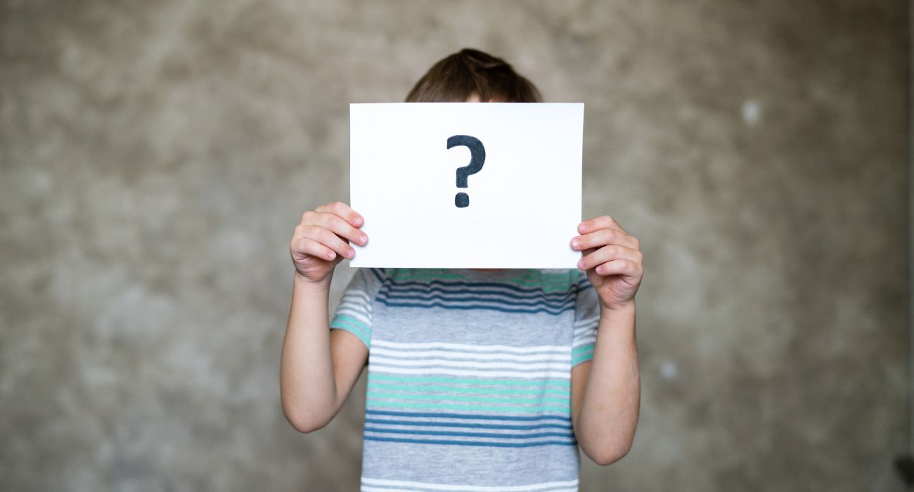 Boy Holding paper with question mark over his face