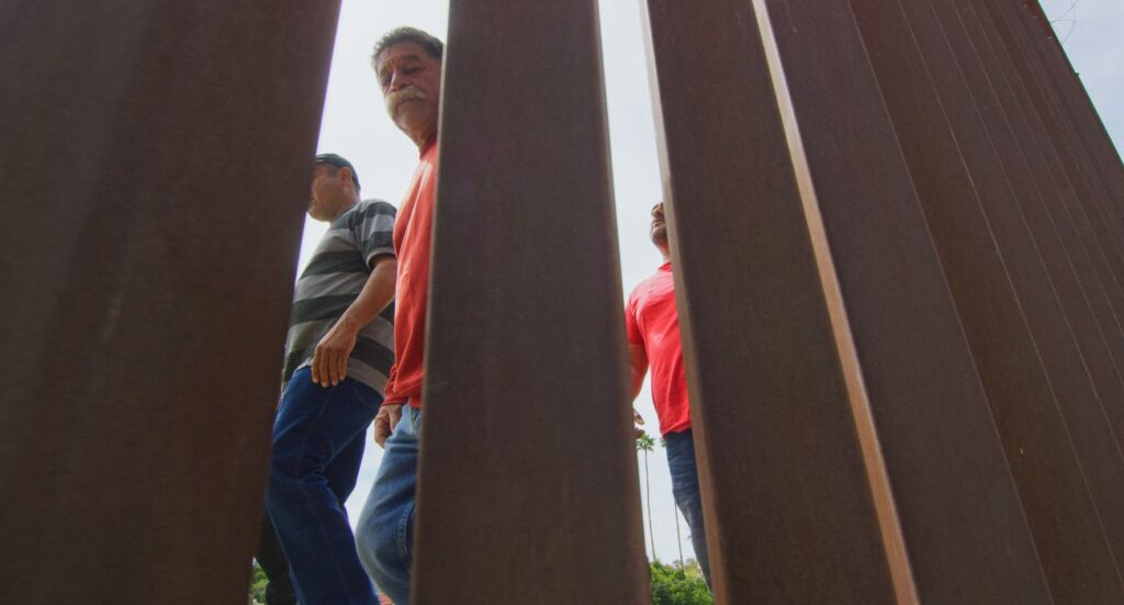 Unlawful migrants walk along southern U.S. border fence