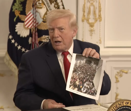President Donald Trump holds up a photograph of Afghan evacuees aboard a U.S. Air Force C-17 during a press conference.